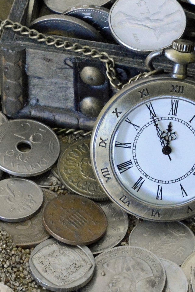 Много монет и карманные часы на песке