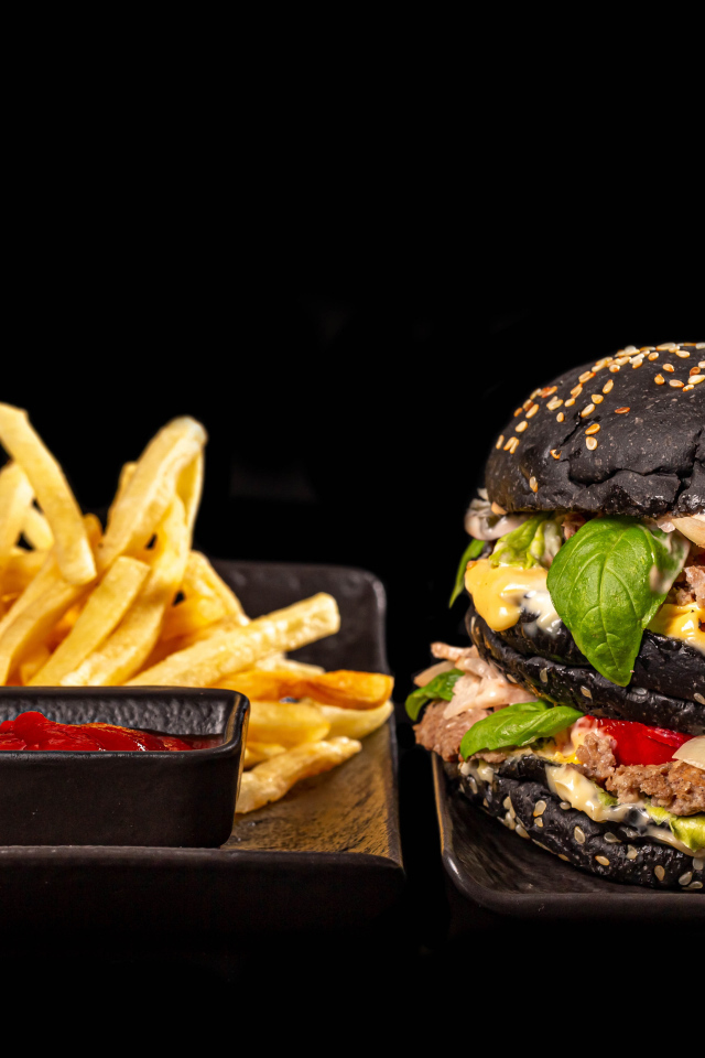 Большой черный гамбургер с картофелем фри и кетчупом 