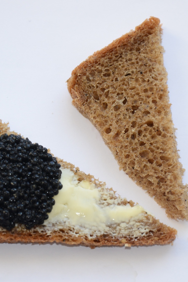 Бутерброды из черного хлеба с черной икрой на сером фоне