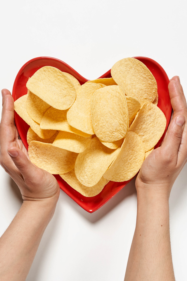 Чипсы в красной тарелке на белом фоне
