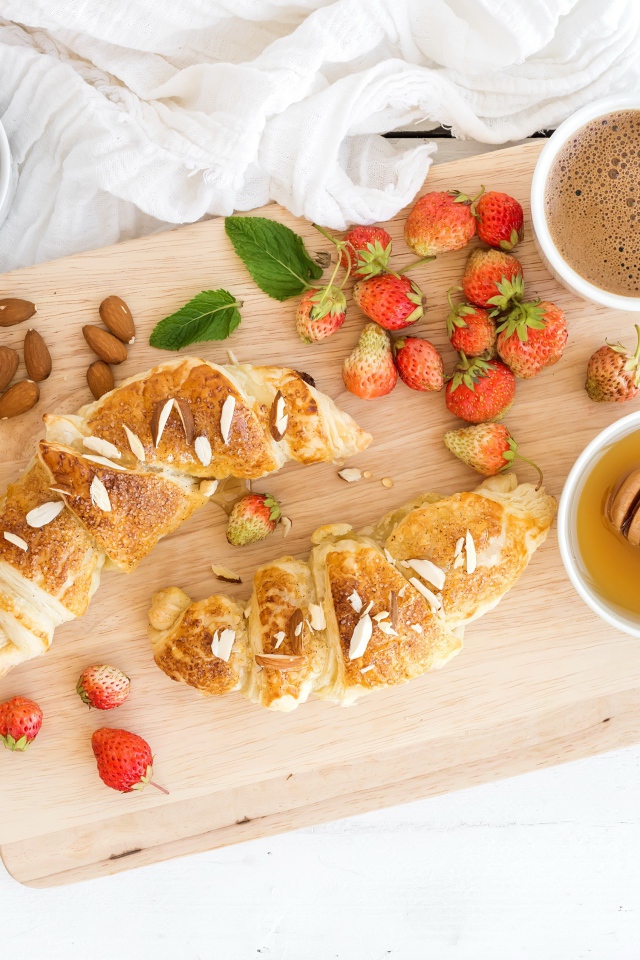 Круассаны на столе с орехами, клубникой и кофе