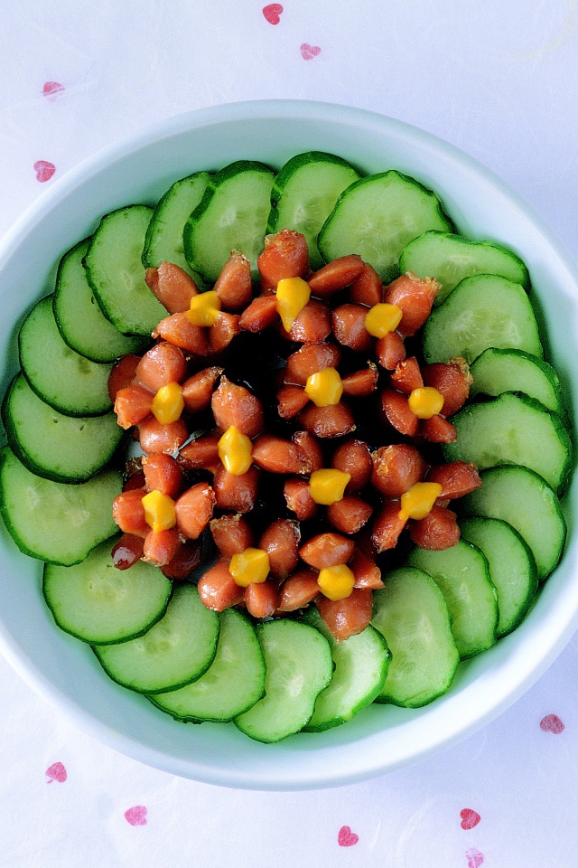 Огурцы с сосисками в тарелке на столе