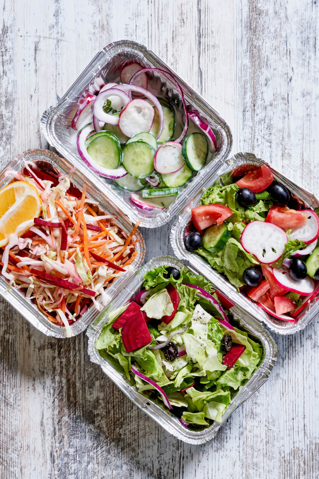 Разные овощные салаты в тарелках на сером столе 