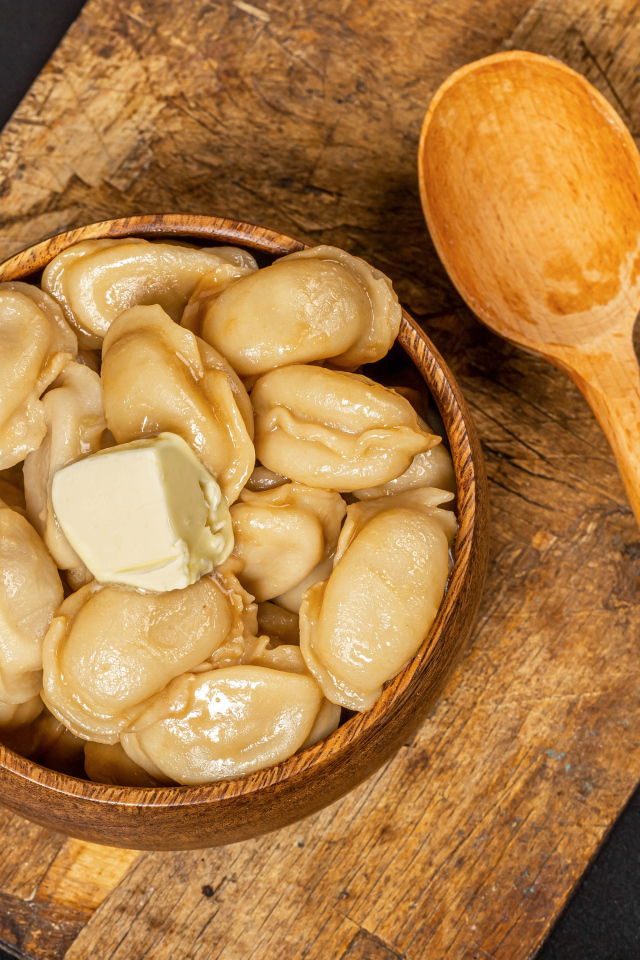 Пельмени в деревянной миске с маслом