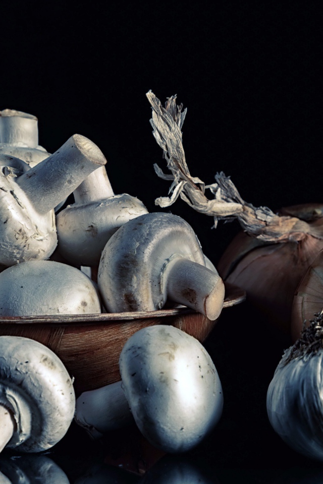 Свежие шампиньоны с луком и чесноком на черном фоне