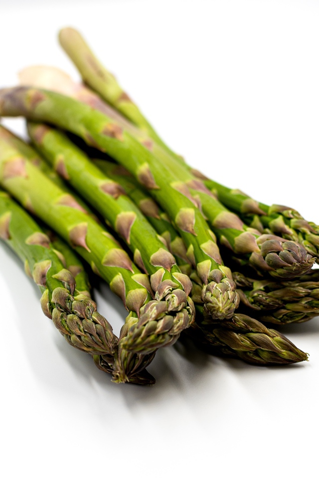 Свежая зеленая спаржа на белом столе