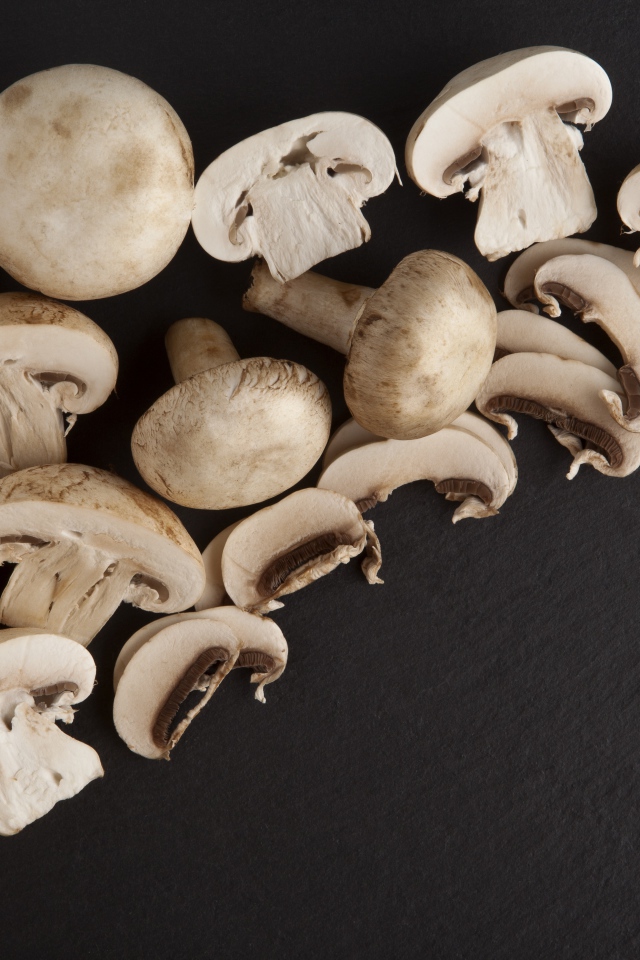 Свежие нарезанные шампиньоны на сером фоне