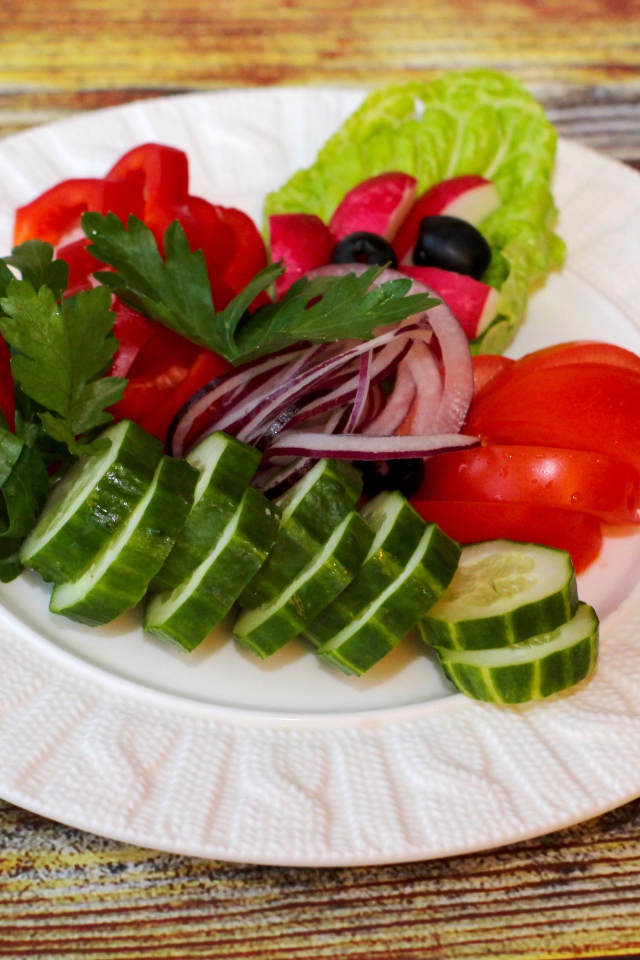 Свежие овощи на белой тарелке на деревянном фоне