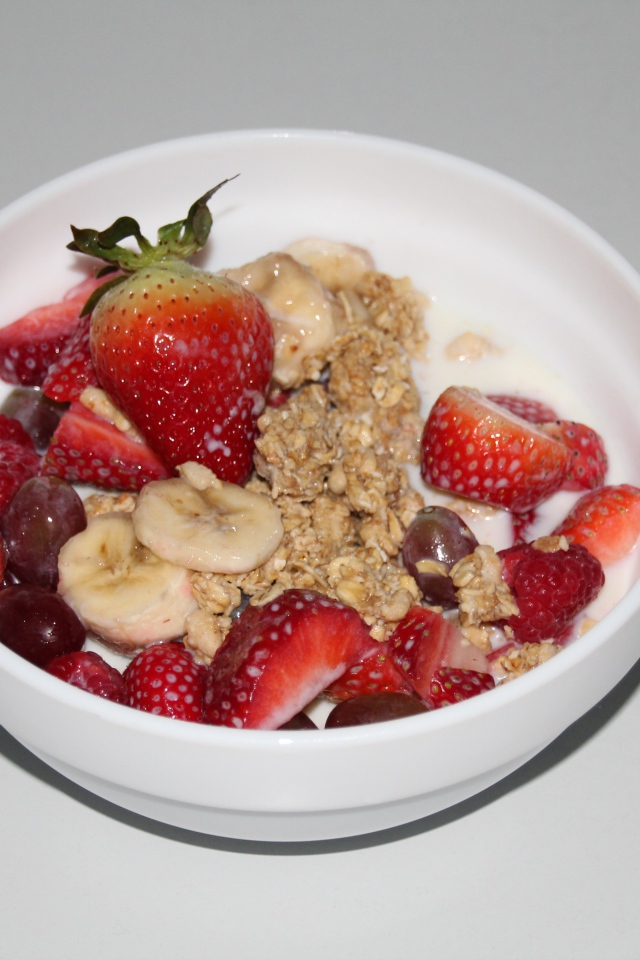 Мюсли с молоком и ягодами на сером столе