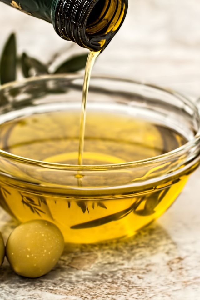 Оливковое масло с оливками на столе 