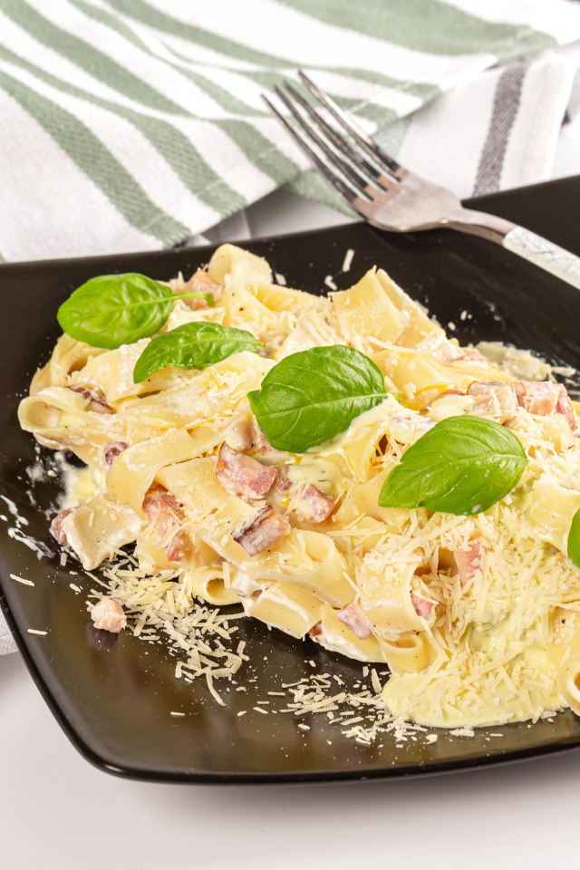 Макароны на тарелке с тертым сыром и кусочками мяса