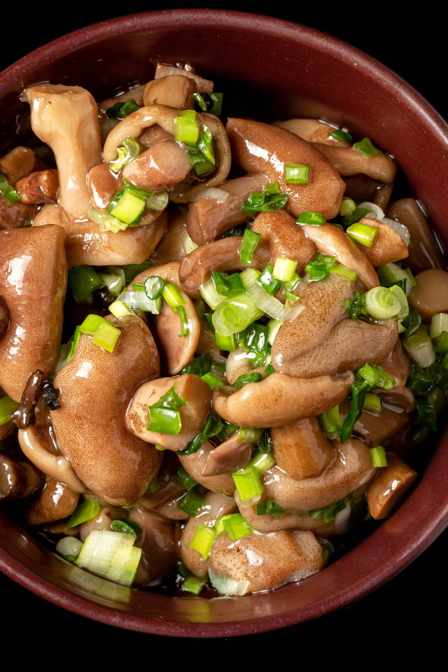 Маринованные маслята с зеленью в тарелке