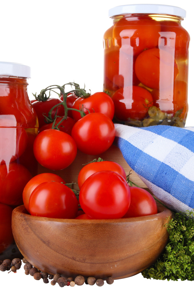 Маринованные помидоры в банках на столе со свежими