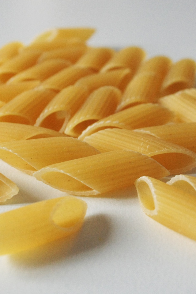 Сырые желтые макароны на сером фоне