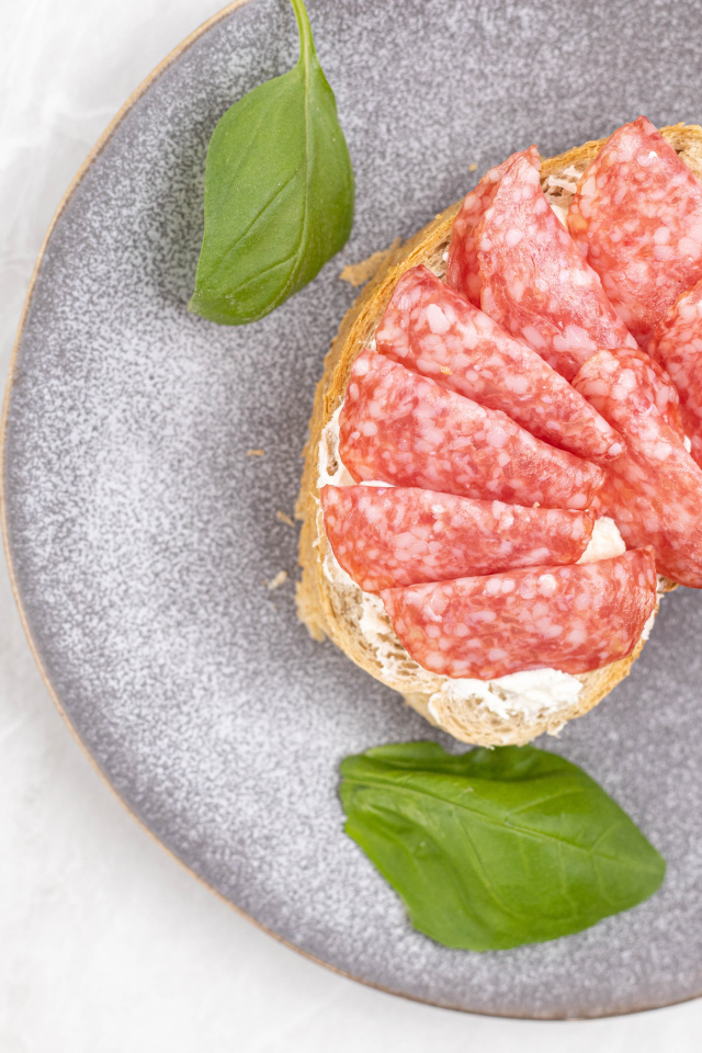 Бутерброд с маслом и колбасой на тарелке