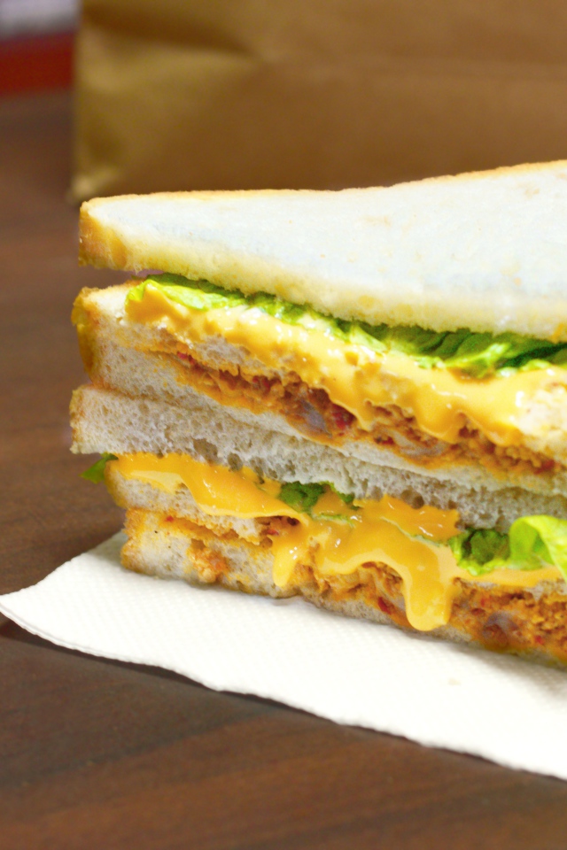 Сэндвич с сыром и листьями салата на столе