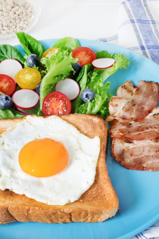 Яичница с хлебом на тарелке с салатом и беконом 