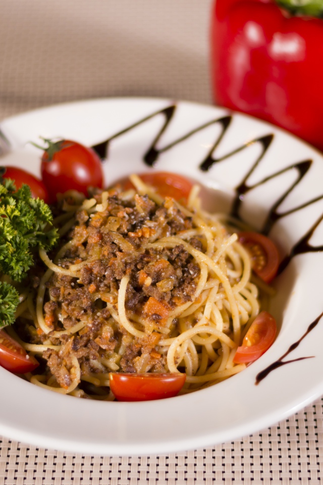 Спагетти с фаршем и помидорами в тарелке 
