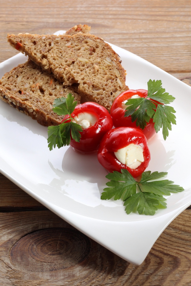 Фаршированный перец на большой белой тарелке с хлебом