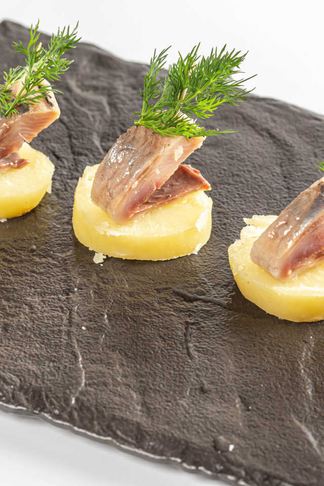 Три куска вареного картофеля с сельдью и укропом