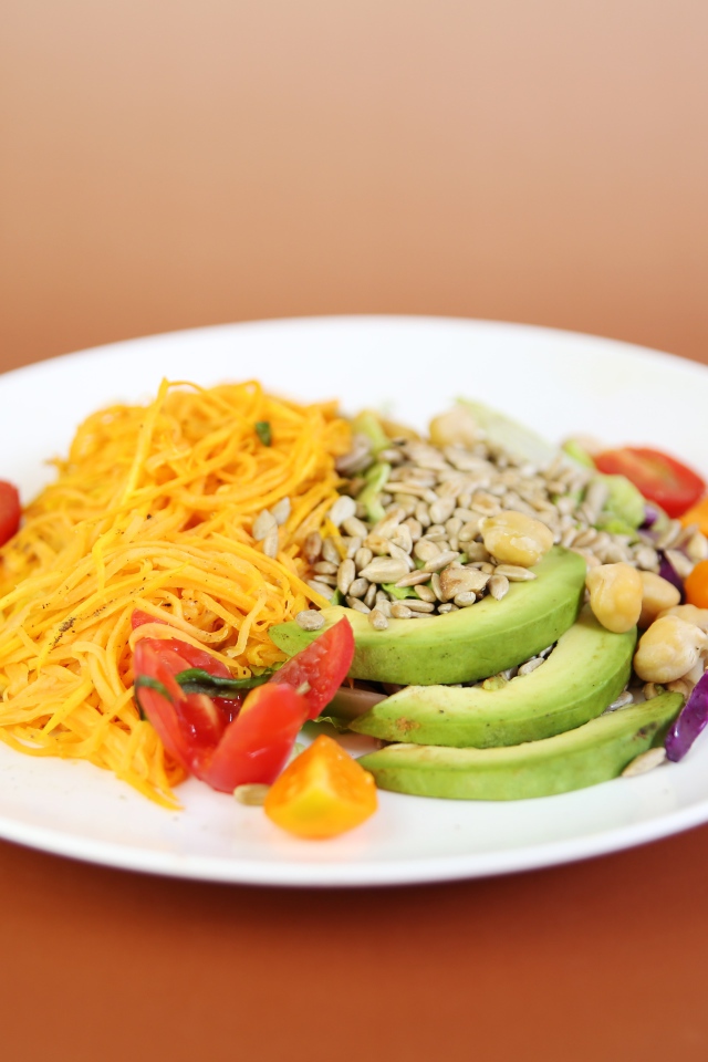 Овощи в белой тарелке на оранжевом фоне 