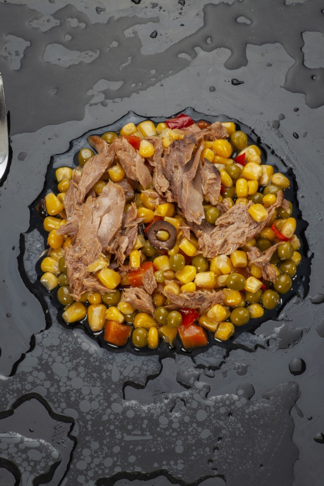 Овощи с мясом и столовыми приборами на черной поверхности