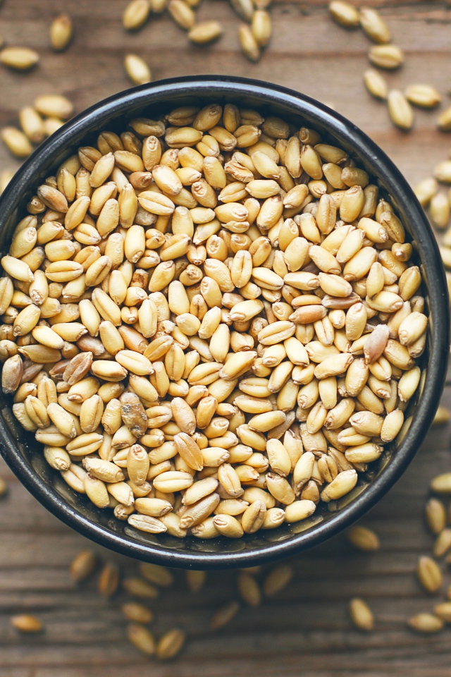 Зерна пшеницы в черной кружке на столе 