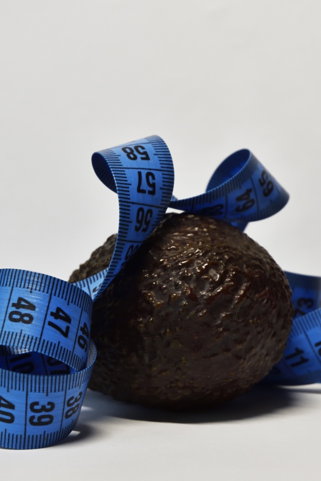 Авокадо с сантиметром на сером фоне