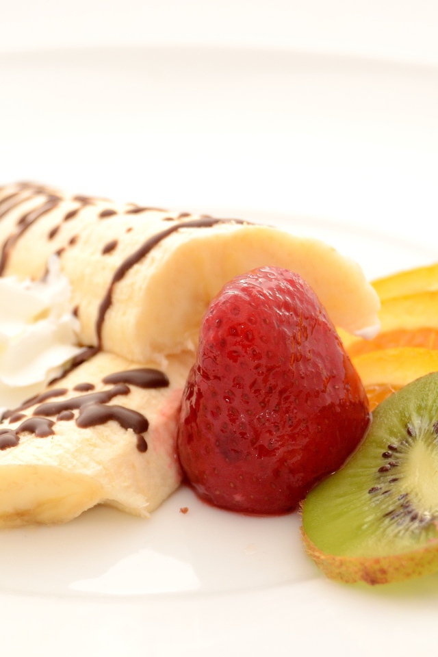 Бананы, киви и клубника на тарелке со сливками