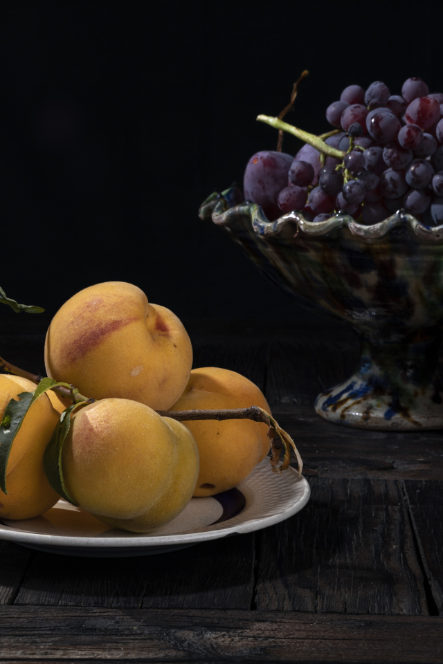 Красивые сочные персики на столе с виноградом