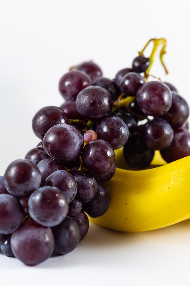Гроздь розового винограда и бананы на белом фоне