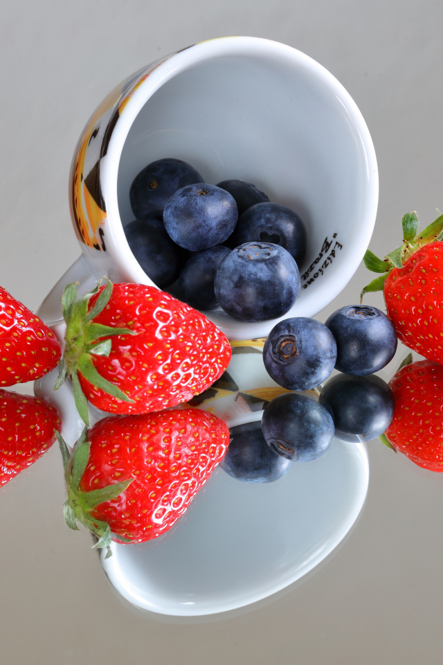 Чашка с ягодами черники и клубники на столе