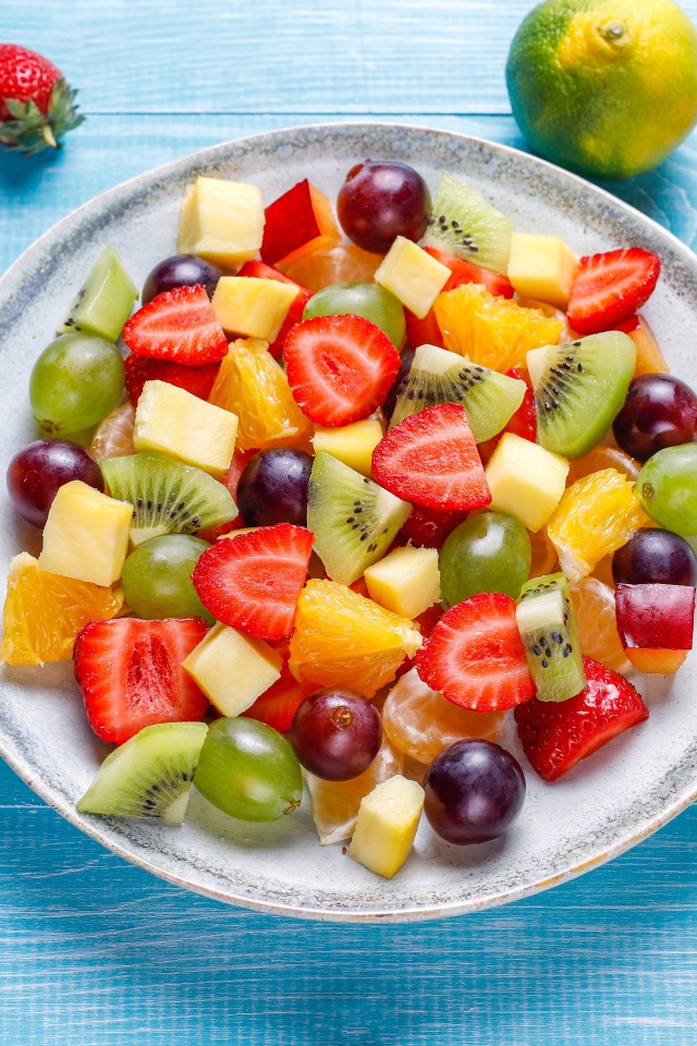 Вкусный салат из свежих овощей и ягод на голубом столе