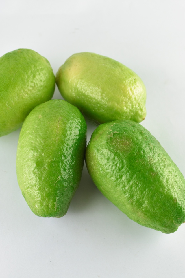 Четыре зеленых лимона на белом фоне