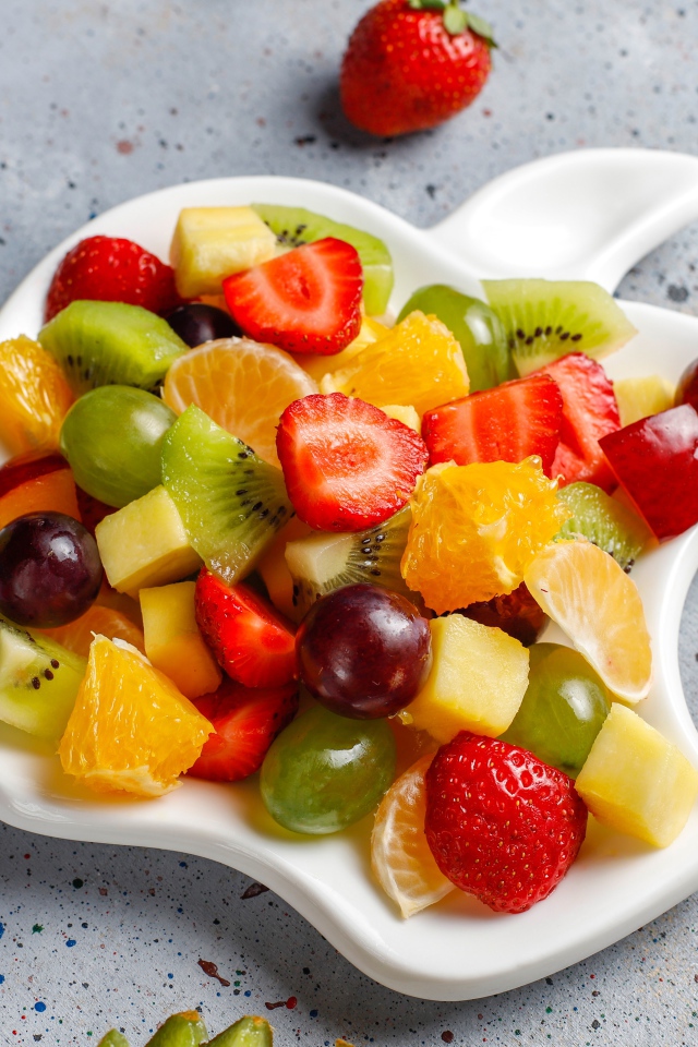 Фруктовый салат на белой тарелке на столе 