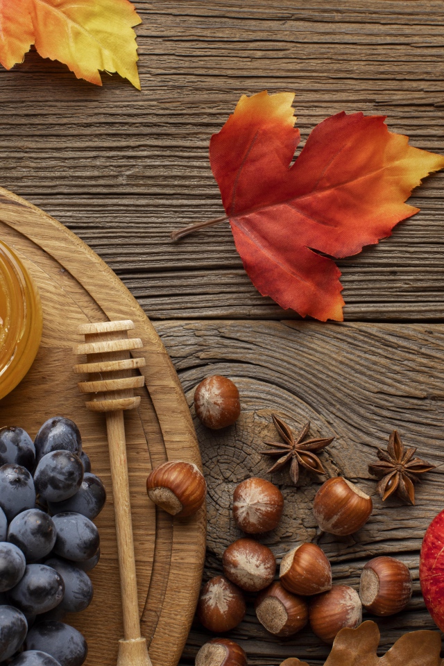 Мед на столе с виноградом, орехами и яблоками