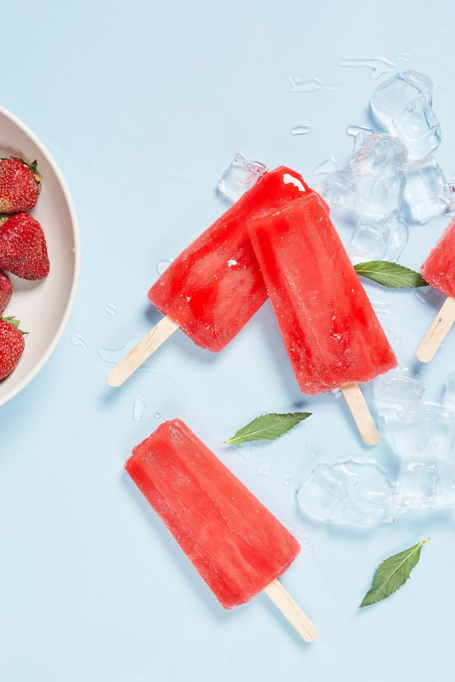 Мороженое со льдом и ягодами клубники на голубом фоне 