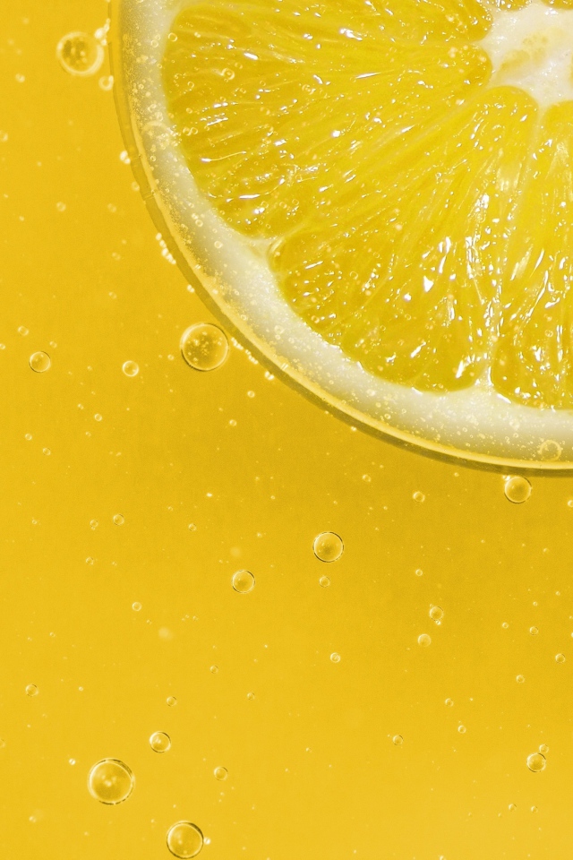 Лимон на желтом фоне с каплями воды