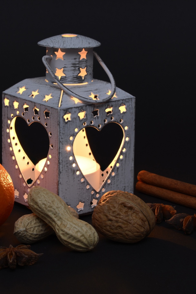 Мандарин, орехи, специи и фонарь на черном фоне