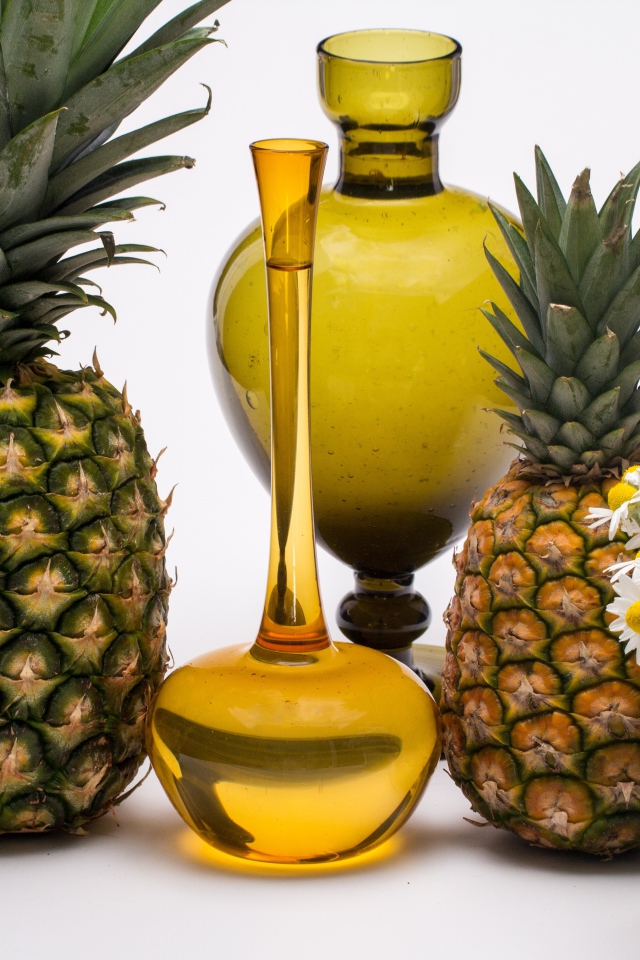 Ананасы на столе с маслом и ромашками