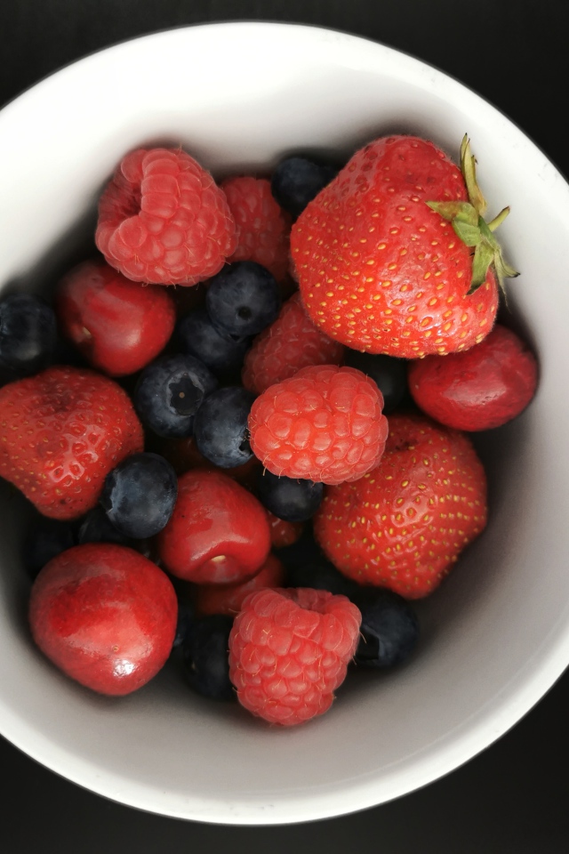 Спелые свежие ягоды в белой тарелке на белом фоне