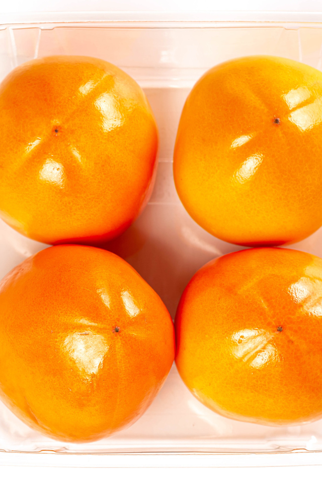 Спелая хурма с лотке на белом фоне