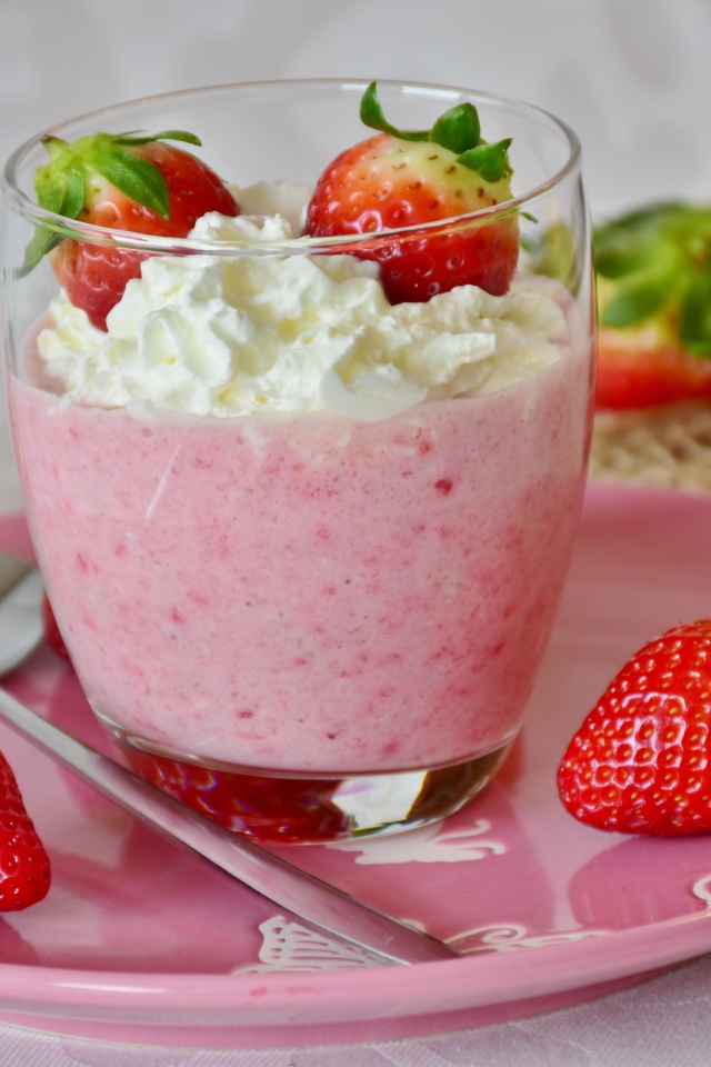 Ягоды клубники со взбитыми сливками на столе 