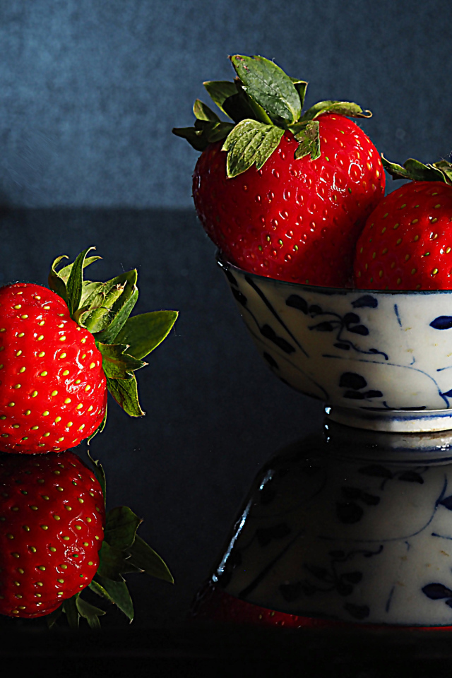 Три красные клубники в миске на столе