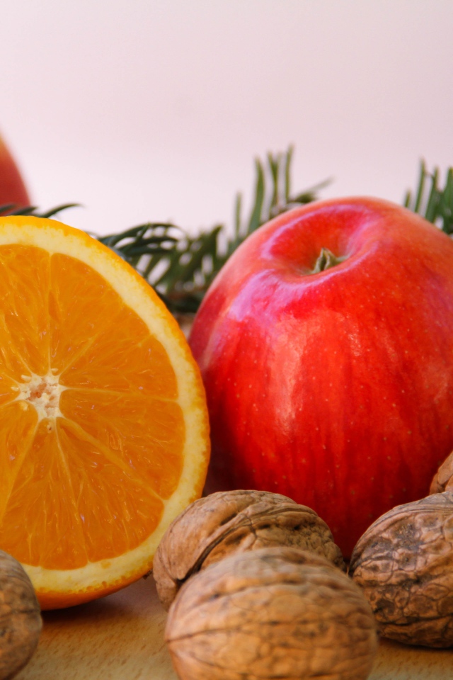 Грецкие орехи с апельсинами и яблоками на сером фоне 