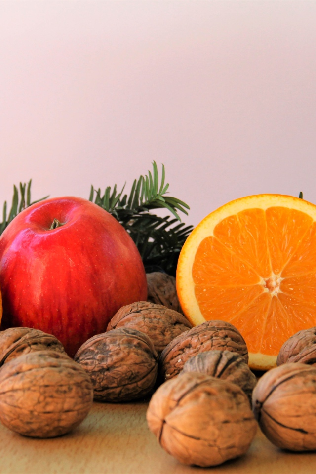 Грецкие орехи с апельсинами и яблоками на столе