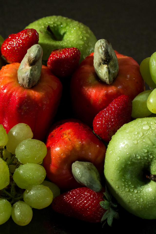 Мокрые яблоки, виноград и клубника на столе 