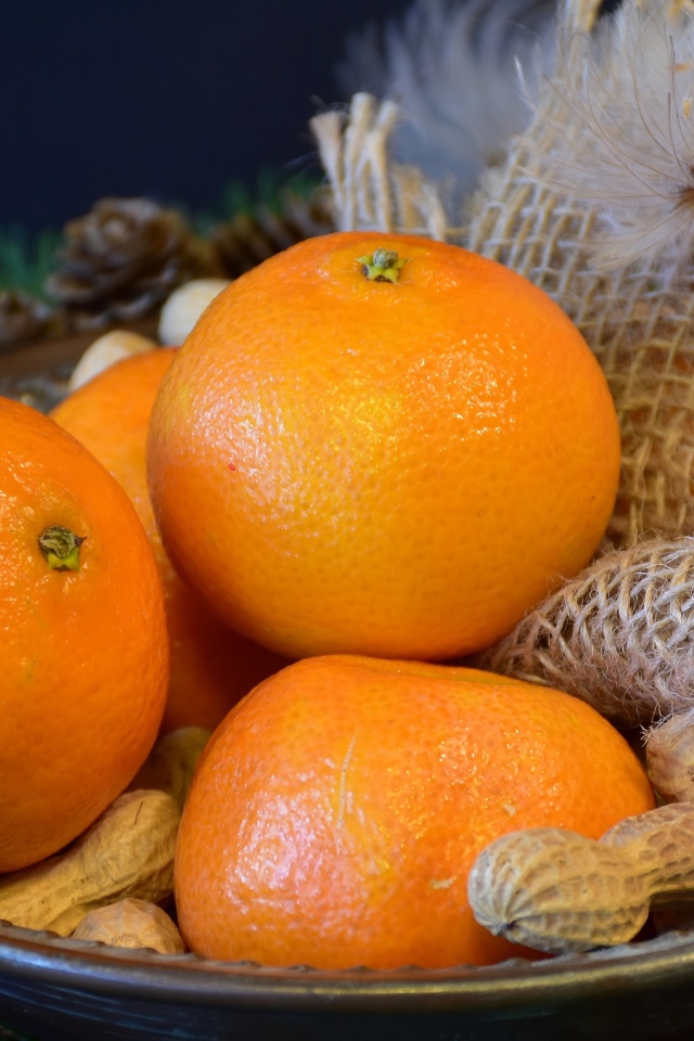 Желтые апельсины с арахисом  на тарелке