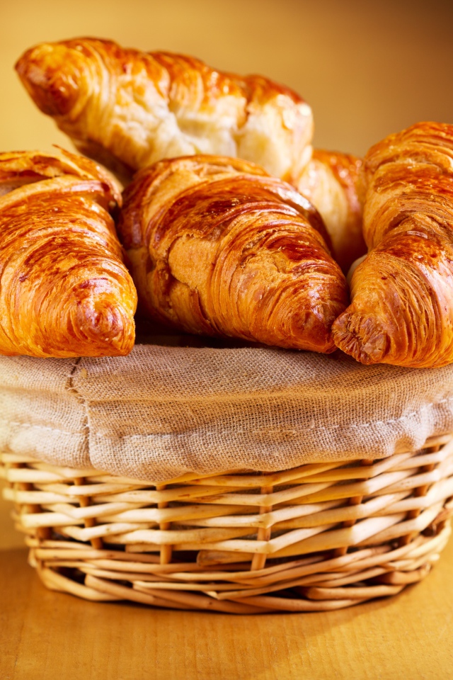 Baked ruddy croissants on the table in a basket