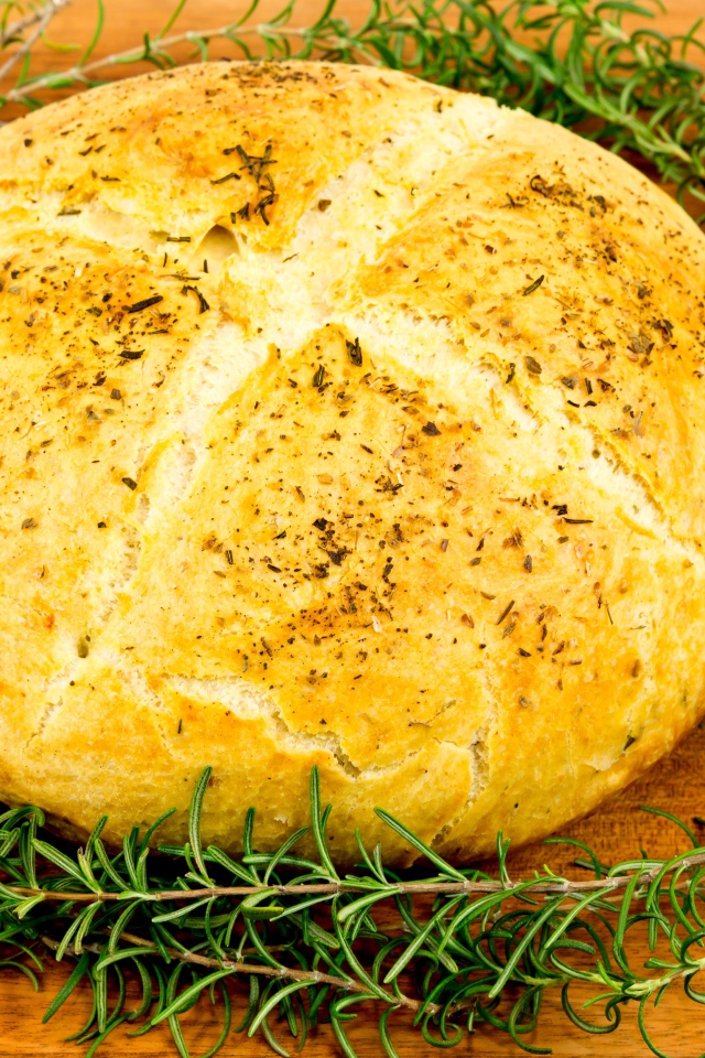 Буханка свежего ароматного хлеба с розмарином на столе